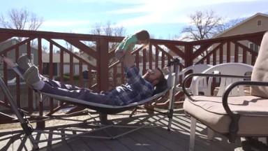 Denver, Colorado, United States: Dad playing with toddler on outdoor deck hammock in summer sun.