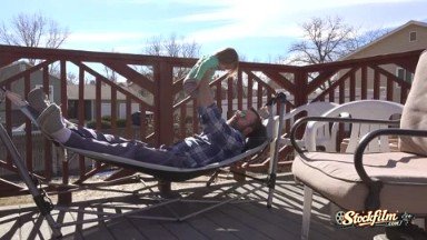 Denver, Colorado, United States: Dad playing with toddler on outdoor deck hammock in summer sun.