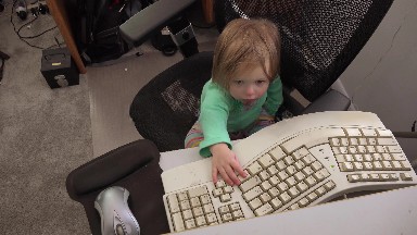 Toddler working on computer typing on keyboard mousing day job.