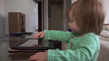 Toddler tablet computer taps and swipes closeup on coffee table.