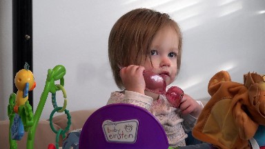 Dad putting rose colored sunglasses on toddler in baby einstein office.