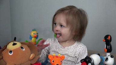 Toddler soothing teething pain with fingers in mouth on toy setup.