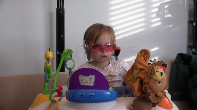 Toddler takes off rose colored glasses on toddler in baby einstein office.