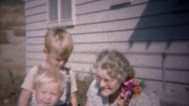 1949: Blonde baby brothers playing with grandma with corsage.