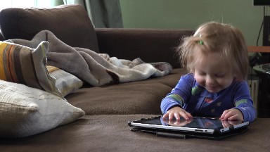 Toddler gets distracted from tablet computer in blue pajamas. DENVER, COLORADO