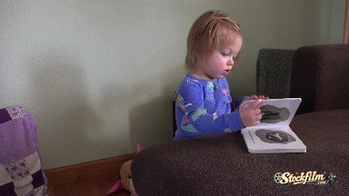 Cute Caucasian Toddler Reading Baby Book in Blue Pajamas. Denver, Colorado