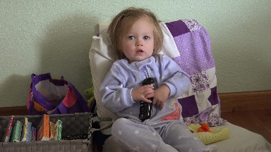 Baby blue pajamas holding tv remote controller seated with books. DENVER,