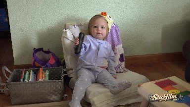 Baby in Duck Hat Sitting on Small Chair with TV Remote Playing. Denver, Colorado,