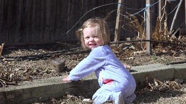 Baby kneeling outside sunny playing with garden backyard rocks. DENVER, COLORADO