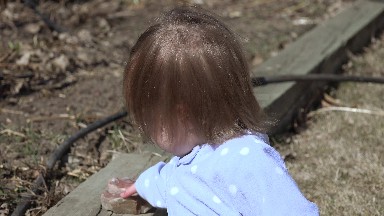Closeup baby blonde brown hair blowing in wind playing rocks. DENVER, COLORADO