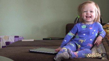 Laughing Baby Playing With Tablet Computer On Brown Couch. Denver, Colorado