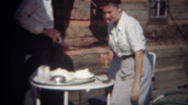 1944: Man Serving Fancy Food to Wife at Vacation Log Cabin Outdoor Dining.