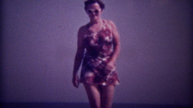 1937: Women in colorful floral pattern bathing suit with round white sunglasses