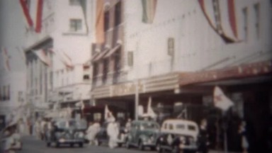 1944: Downtown mainstreet city patriotic flags waving above the street.