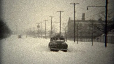 1944: Cars driving unplowed winter snow covered streets sliding around. TROY,