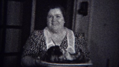 1944: Mom carries roast food to diner table wearing polka dot dress. MIAMI,