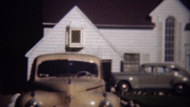 1946: Classic cars parked at fancy white wealthy home shining in sun. SAN DIEGO,