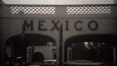 1946: Mexican boarder crossing sign shopping streets and classic car traffic.