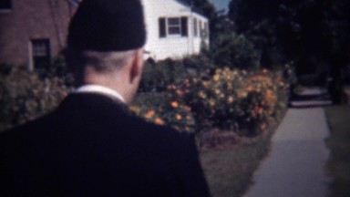 1947: US Navy military soldier walking flowered suburban sidewalk.