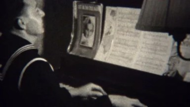 1947: Charming US Navy man playing piano sheet music effortlessly.