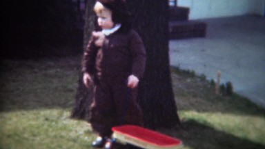 1947: Boy pulling wagon helping dad rake autumn tree leaves.
