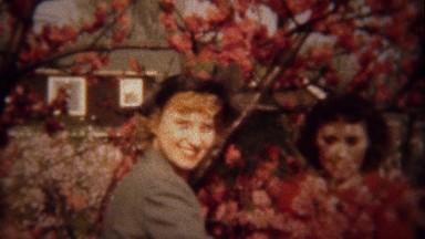 1948: Women wave red flowering tree blossoms sunshine happiness.