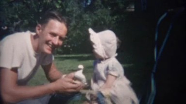 1948: Greaser style man entices uninterested baby with duck toy.