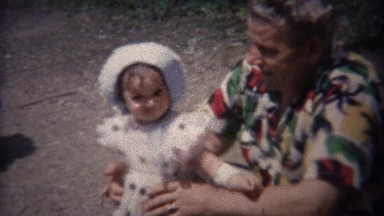 1948: Grandpa colorful tropical pattern shirt holding fashionable baby girl.
