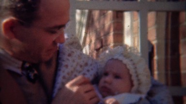 1948: Dad holding newborn baby with mom overlooking cuteness.