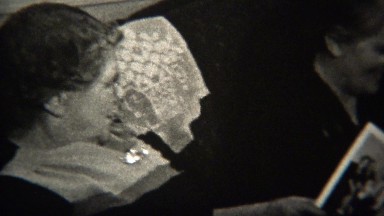 1947: Old women looking at family photos on living room couch.