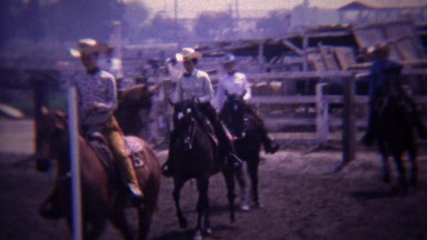 1967: Group horse riders circling track in competition preparation.