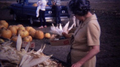 1967: Mature women buying indian colored corn farmstand market.