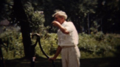 1962: Man pumping water well drinking on hot summer day.