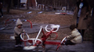 1973: Kids play rotating playground carousel autumn day.