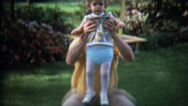 1972: Toddler riding dad's shoulders outdoor backyard play.