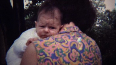 1971: Hippie gypsy shirt mother calming soothing newborn baby.