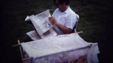 1971: Dad reading newspaper outdoor baby changing table.