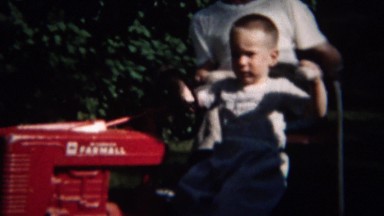 1959: Toddler Riding Toy Red Farmall Tractor Grandpa Watching.