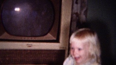 1959: Blonde toddler girl dancing to TV music in living room.