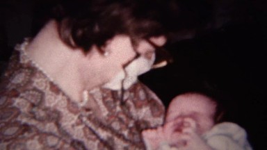 1959: Sick mom wears paper face mask keeps germs away from baby.