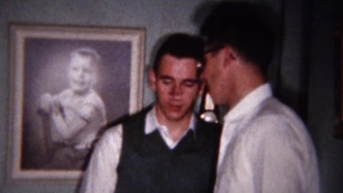 1959: Teenagers plotting with baby portrait picture on background wall.