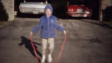1963: Girl confidentially jumps rope in driveway garage door open.