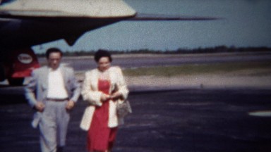 1954: Italian American Couple Exit Airplane Tarmac Walking