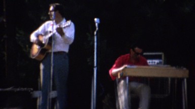 1961: Local music festival band playing on stage people dancing.