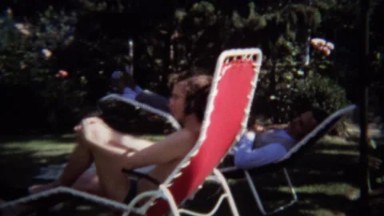 1974: Man Gives Hippie Peace Hand Sign Lounging on Lawn Chairs