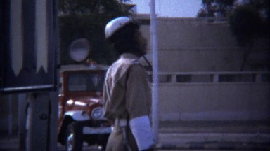 1974: Police Uniform Traffic Officer Patrolling Busy Street Corner.