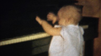 1963: Cute blonde baby learning piano plays keys smiles laughs.