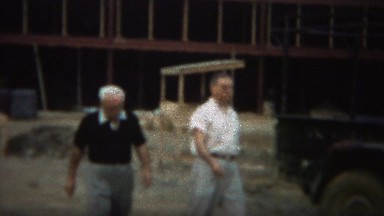 1964: Men inspecting commercial construction building site.