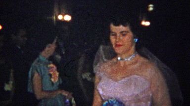 1965: Wedding bride in pink dress solemnly walks down aisle.