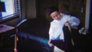 1954: Young Boy Dressing in Navy Blue Pants in Bedroom